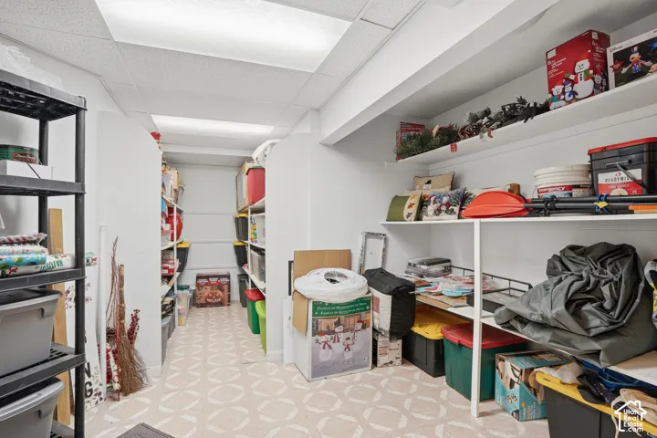 Dedicated storage room featuring built-in shelving, durable utility flooring, and overhead lighting