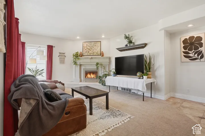 Living area featuring a white fireplace with a mantel, recessed lighting, carpet flooring, and white window blinds
