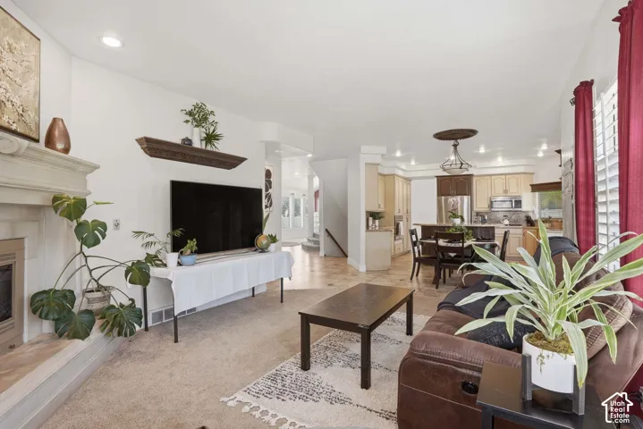 Living area featuring a fireplace with a stone mantel, recessed lighting, and carpet flooring