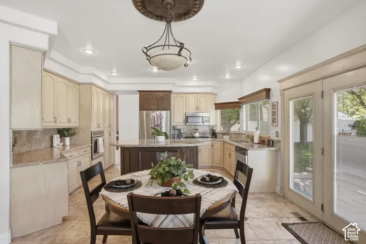 Kitchen featuring light-toned cabinetry, dark-toned island with granite countertop, stainless steel appliances, recessed lighting, and tile flooring