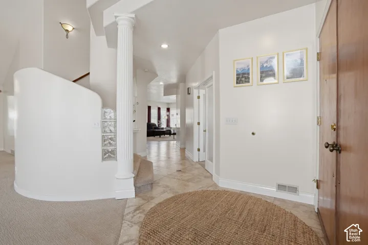 Grand foyer featuring tile flooring, a fluted architectural column, and a curved wall with glass block accents