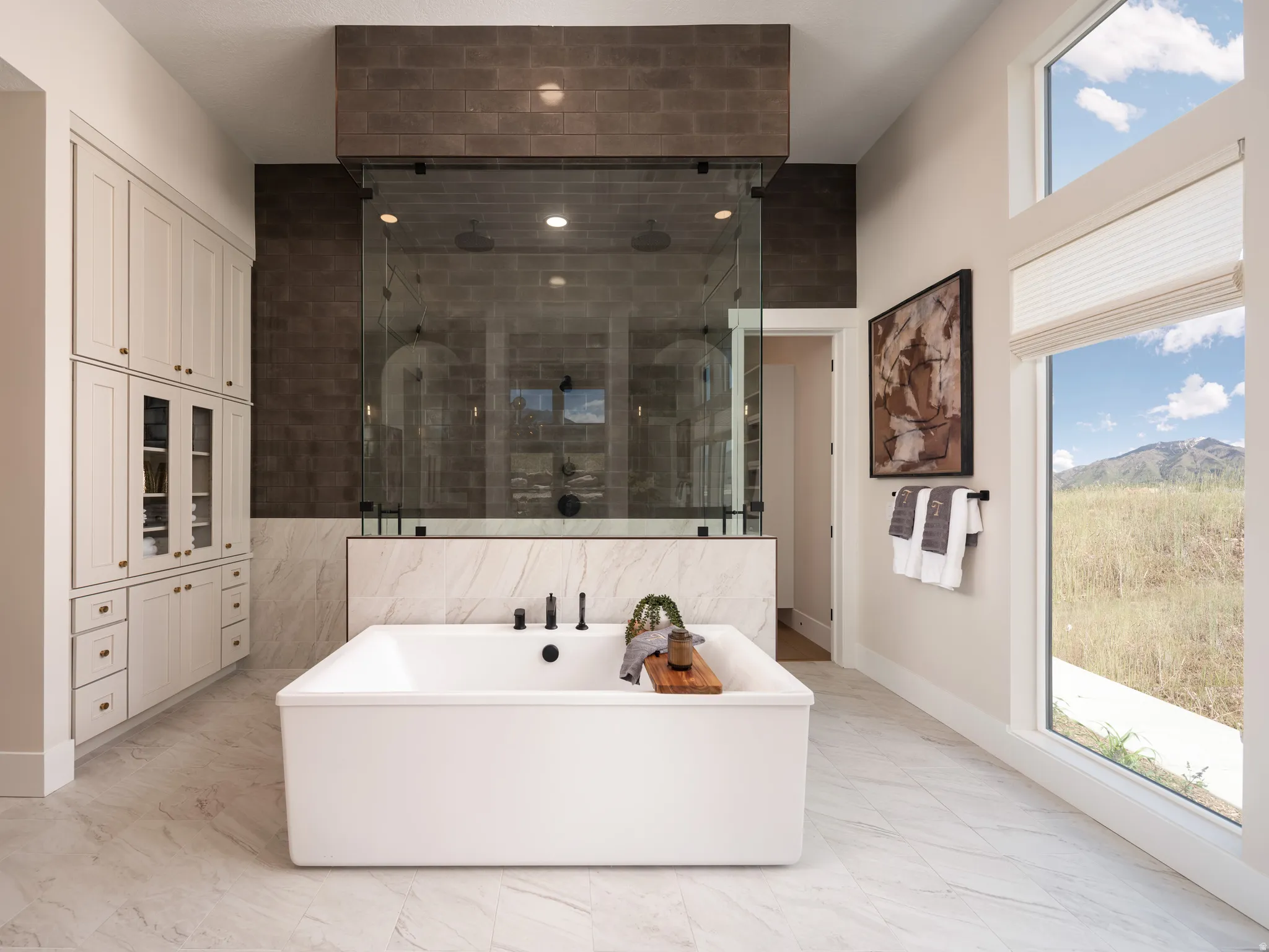 Freestanding soaking tub with matte black fixtures, set against a full-height tiled feature wall