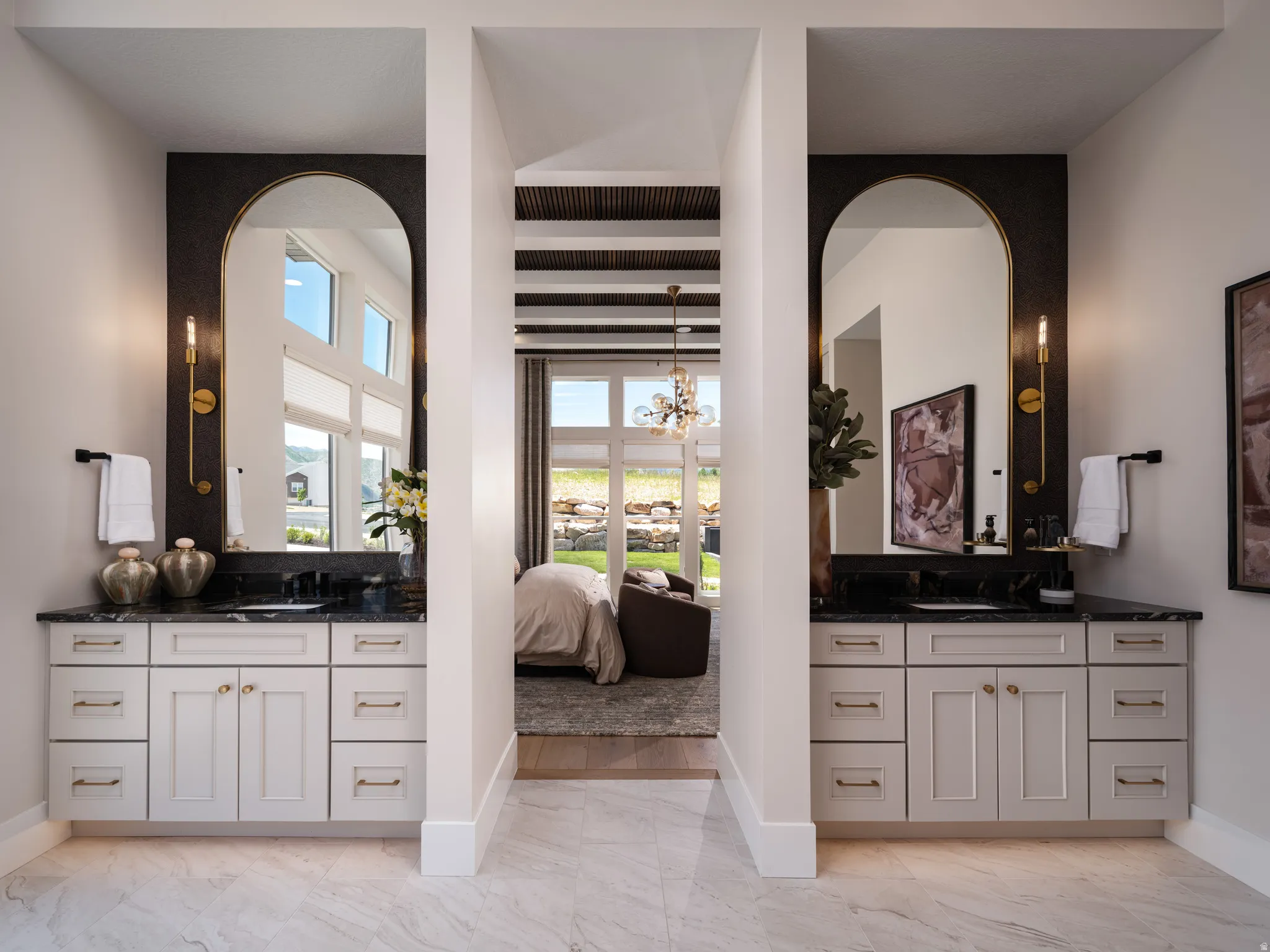 Dual vanity spaces featuring white shaker cabinetry, dark countertops, and oversized arched mirrors