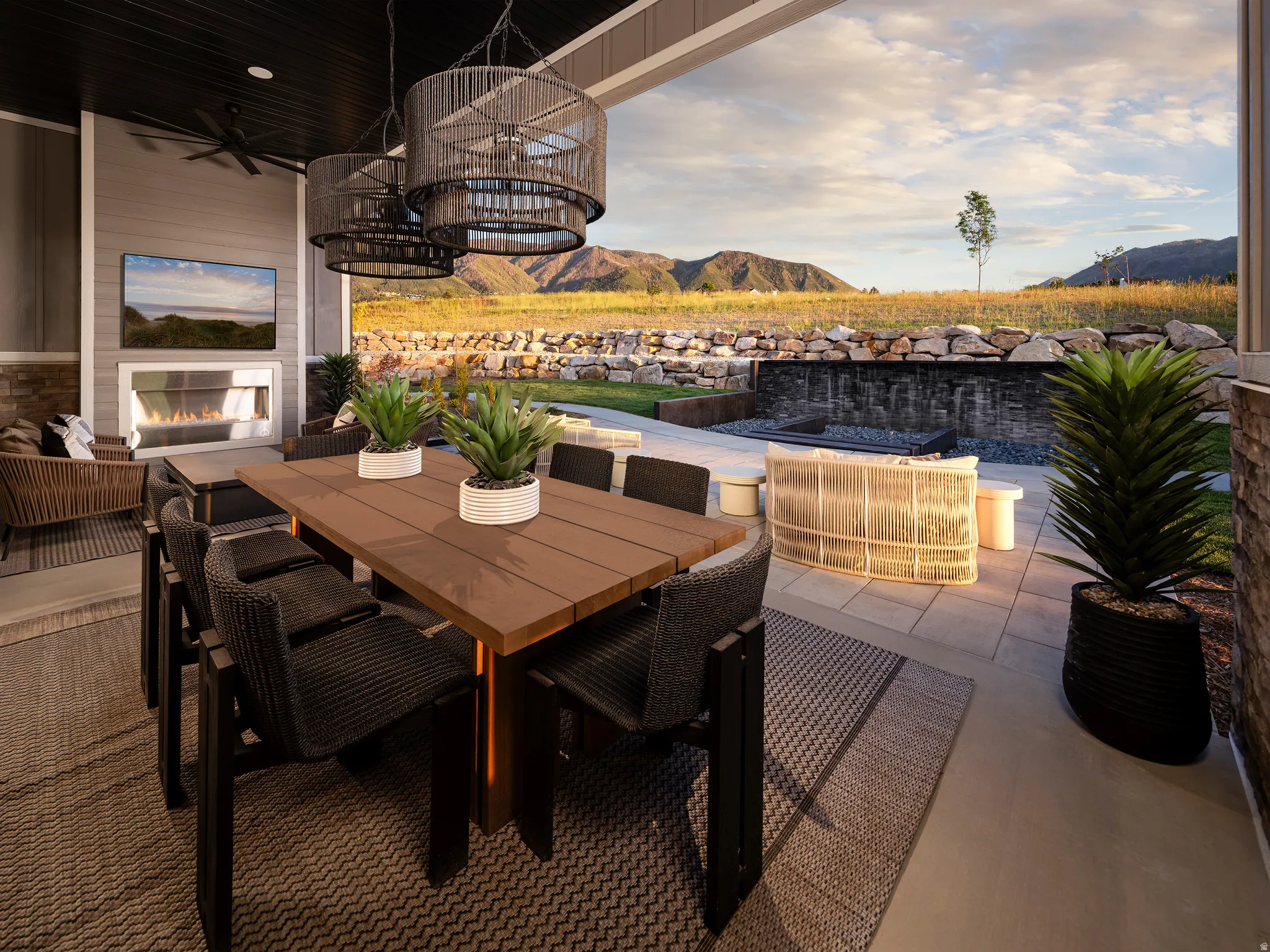 Covered patio featuring a built-in linear fireplace, ceiling fan, and decorative pendant lighting