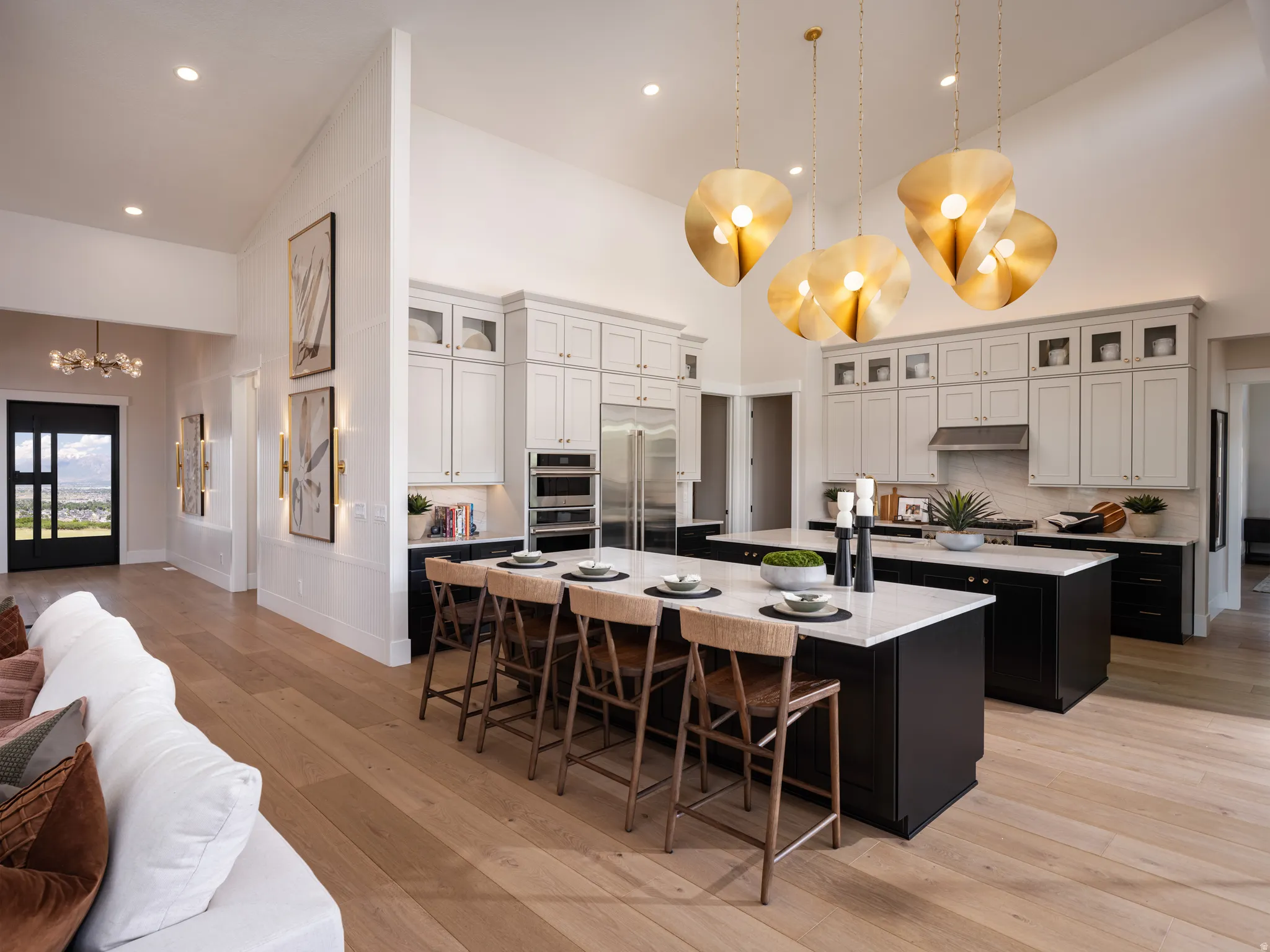 Gourmet kitchen with double islands, light wood-finish flooring, vaulted ceilings, and a suite of stainless steel appliances