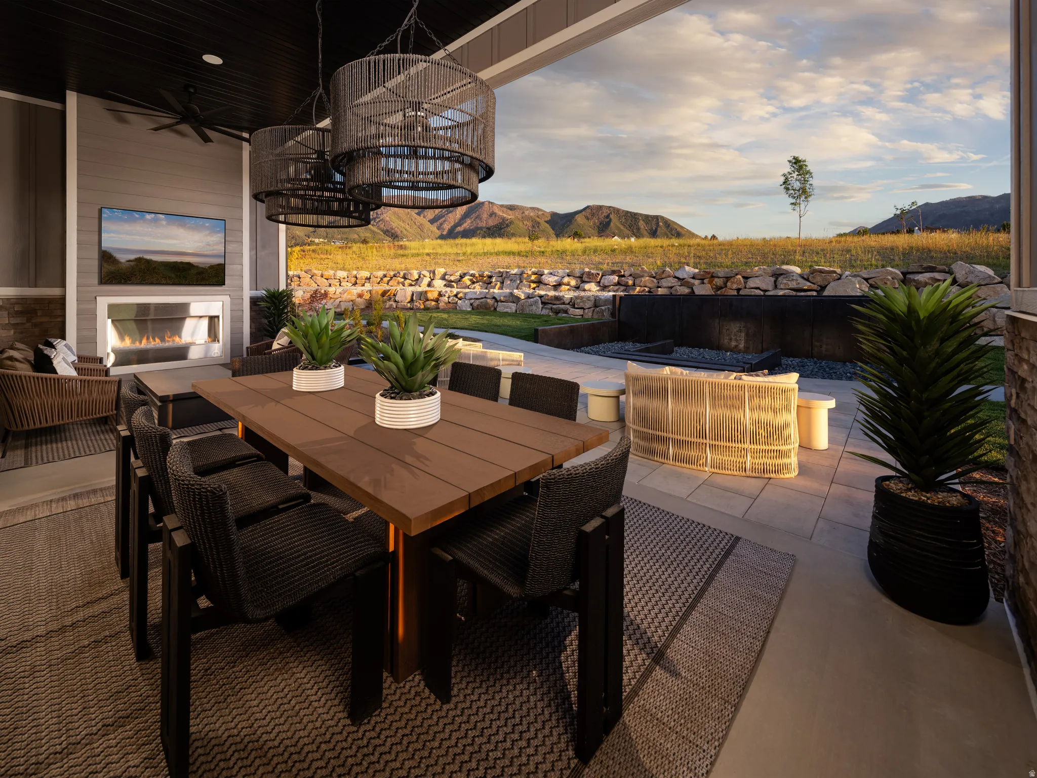 Covered patio featuring a built-in fireplace, wall-mounted television, and a ceiling fan