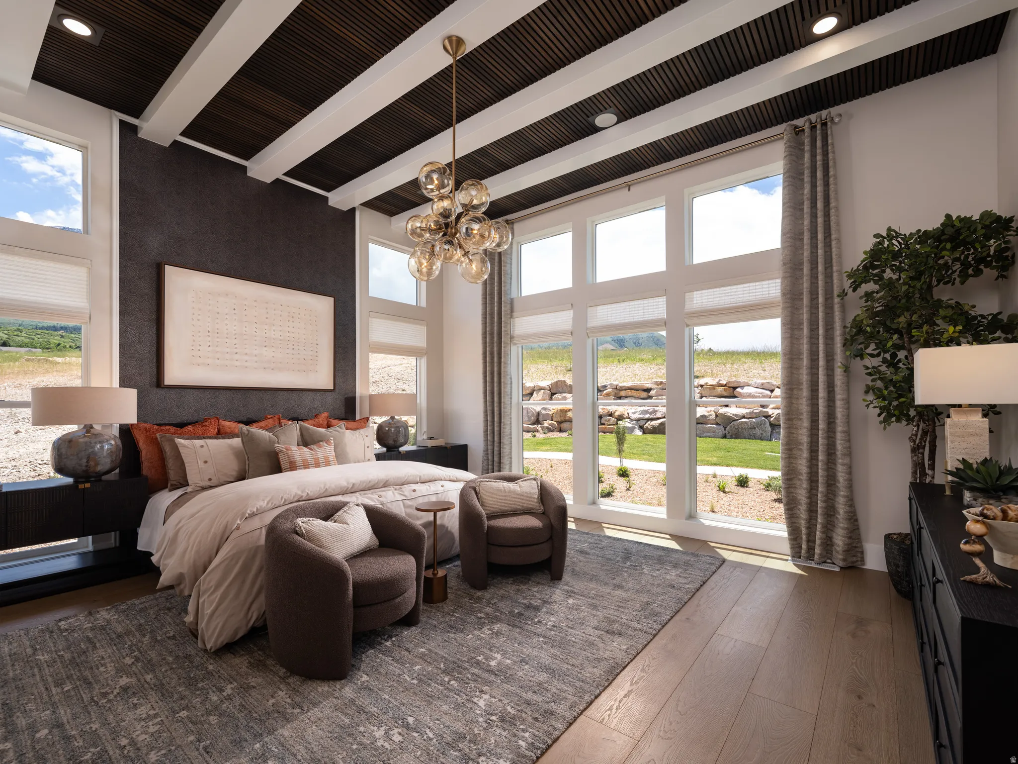 Spacious room featuring expansive windows, wood-finish flooring, a textured accent wall, and a beamed ceiling with recessed lighting