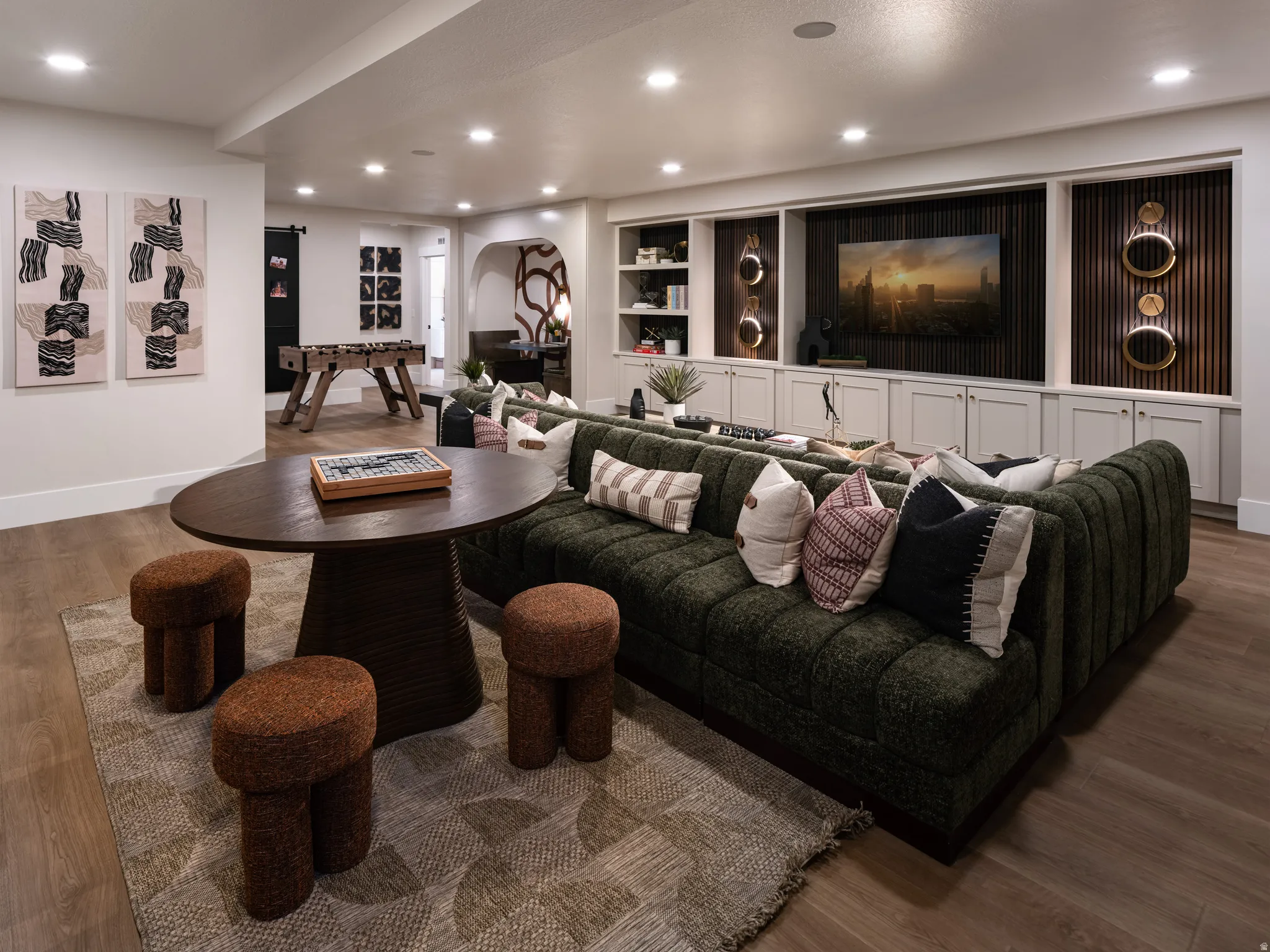 Expansive recreation room featuring wood-finish flooring, recessed lighting, and a built-in media center with cabinetry