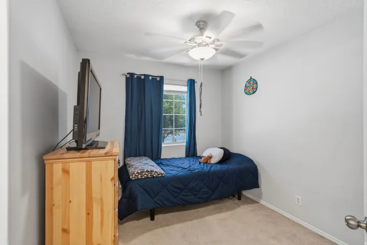 Carpeted room featuring a ceiling fan with integrated lighting, a window with curtains, and light-colored wall paint