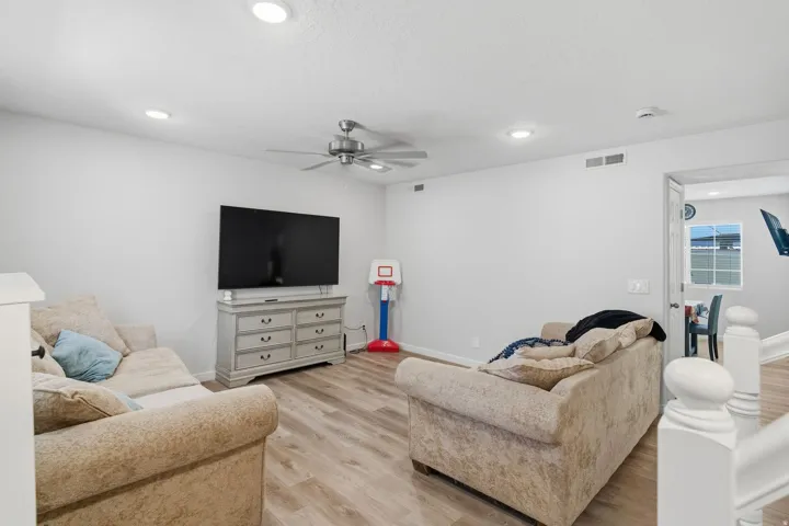 Spacious living area featuring wood-finish flooring, recessed lighting, and a ceiling fan