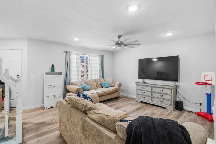 Spacious living area featuring light wood-finish flooring, recessed lighting, and a ceiling fan
