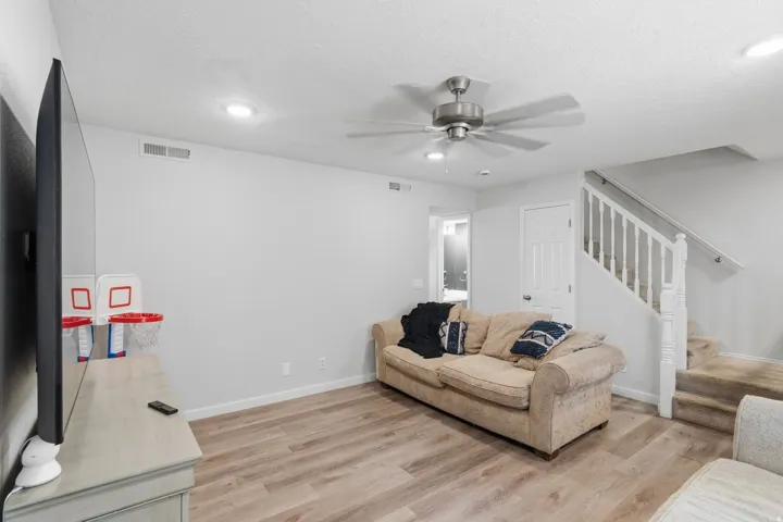 Spacious living area featuring wood-finish flooring, recessed lighting, and a ceiling fan with brushed nickel accents