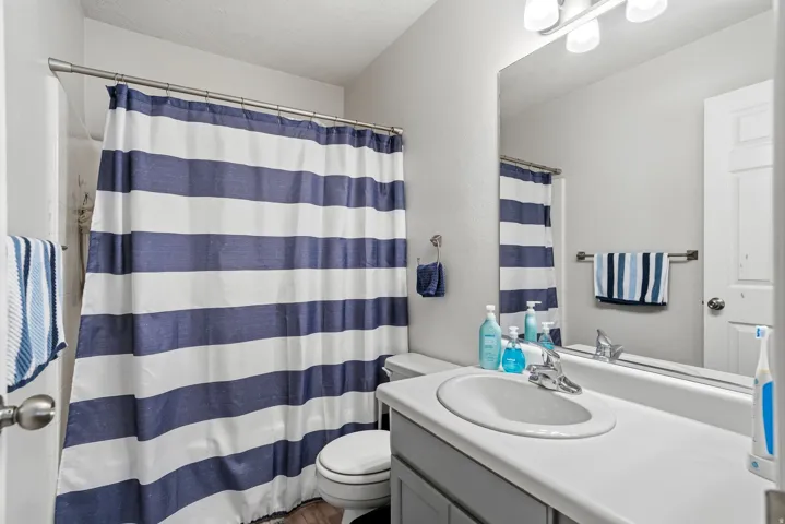 Full bathroom featuring a single vanity with an integrated sink and chrome faucet, a large mirror, and a three-light fixture
