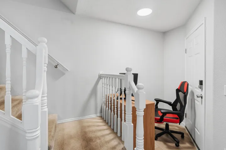 Staircase featuring white balusters and carpeted treads