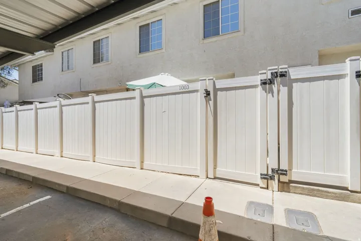 Privacy fence with gate access, featuring white paneling and black hardware