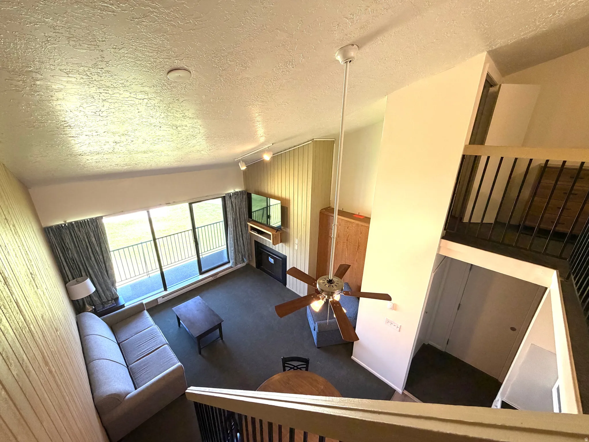 Living area featuring a floor-to-ceiling balcony door with integrated windows, a fireplace, and a ceiling fan with light fixture