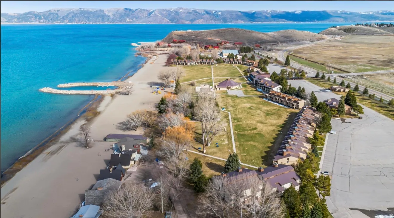 Expansive waterfront property featuring a sandy beach, two rock jetties, and a large grassy area