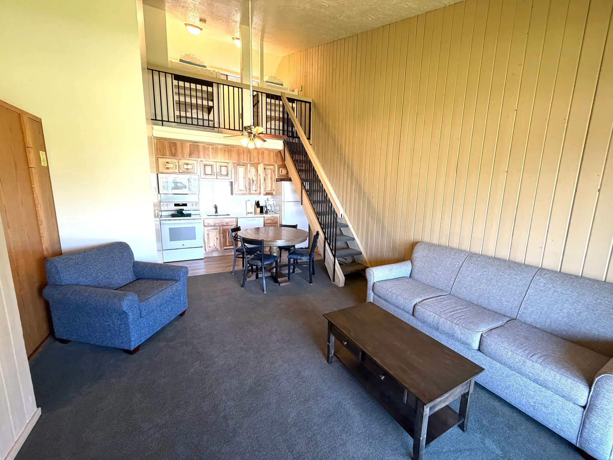 Open-concept living area featuring a kitchen, dining space, and loft access