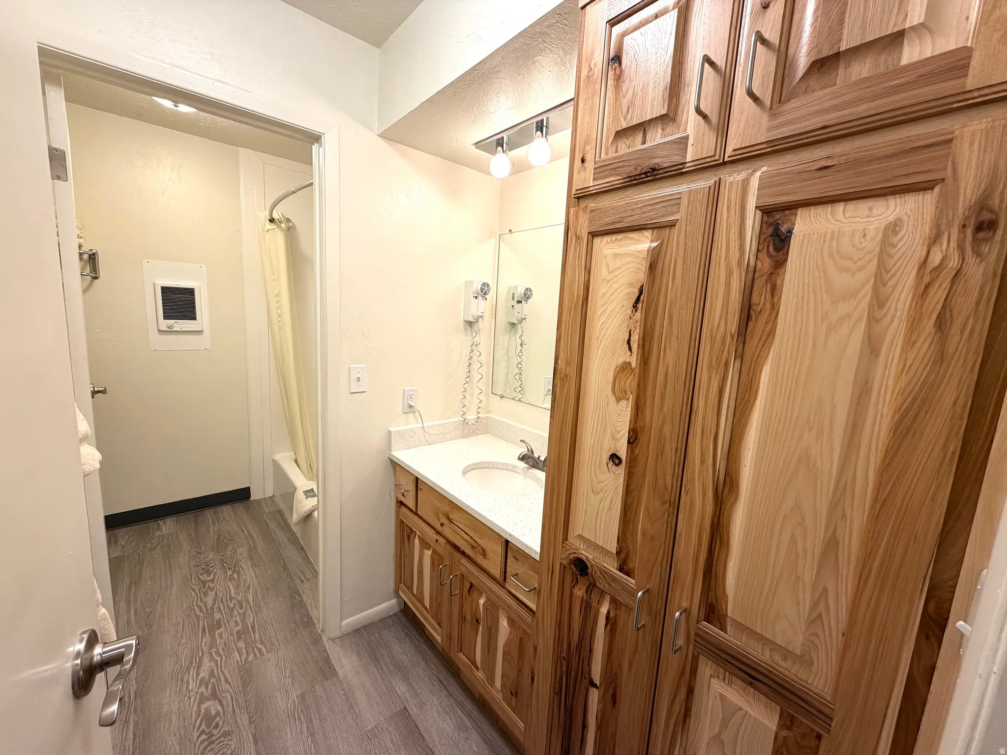 Bathroom featuring wood-finish flooring, a vanity with wood cabinetry, and a white countertop