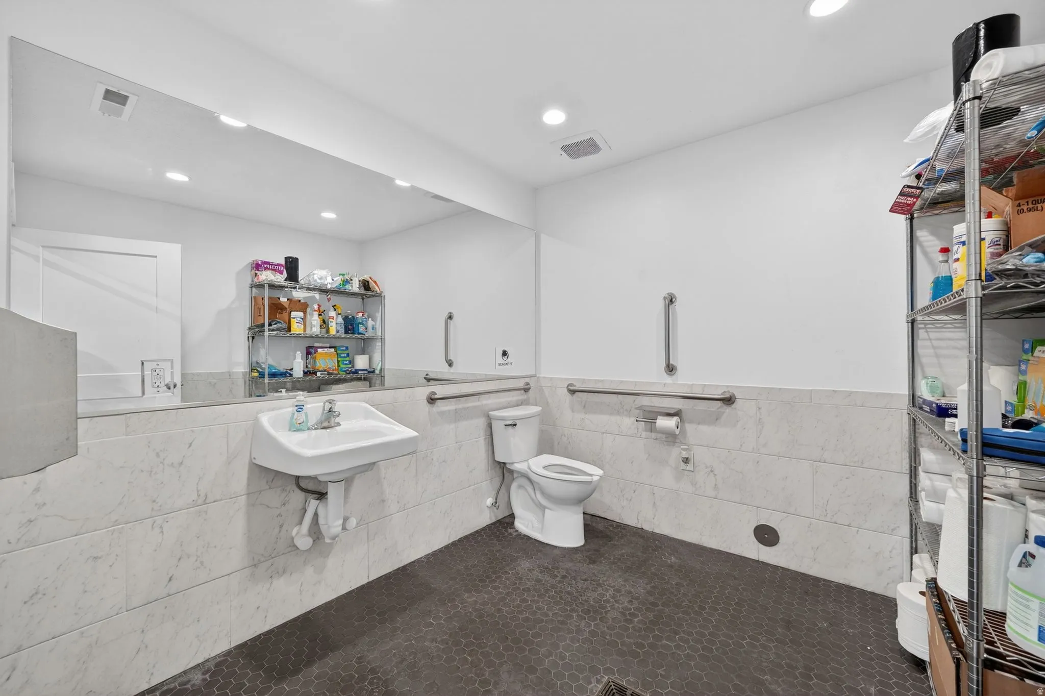 Restroom featuring a wall-mounted sink, toilet, and a full-width wall mirror