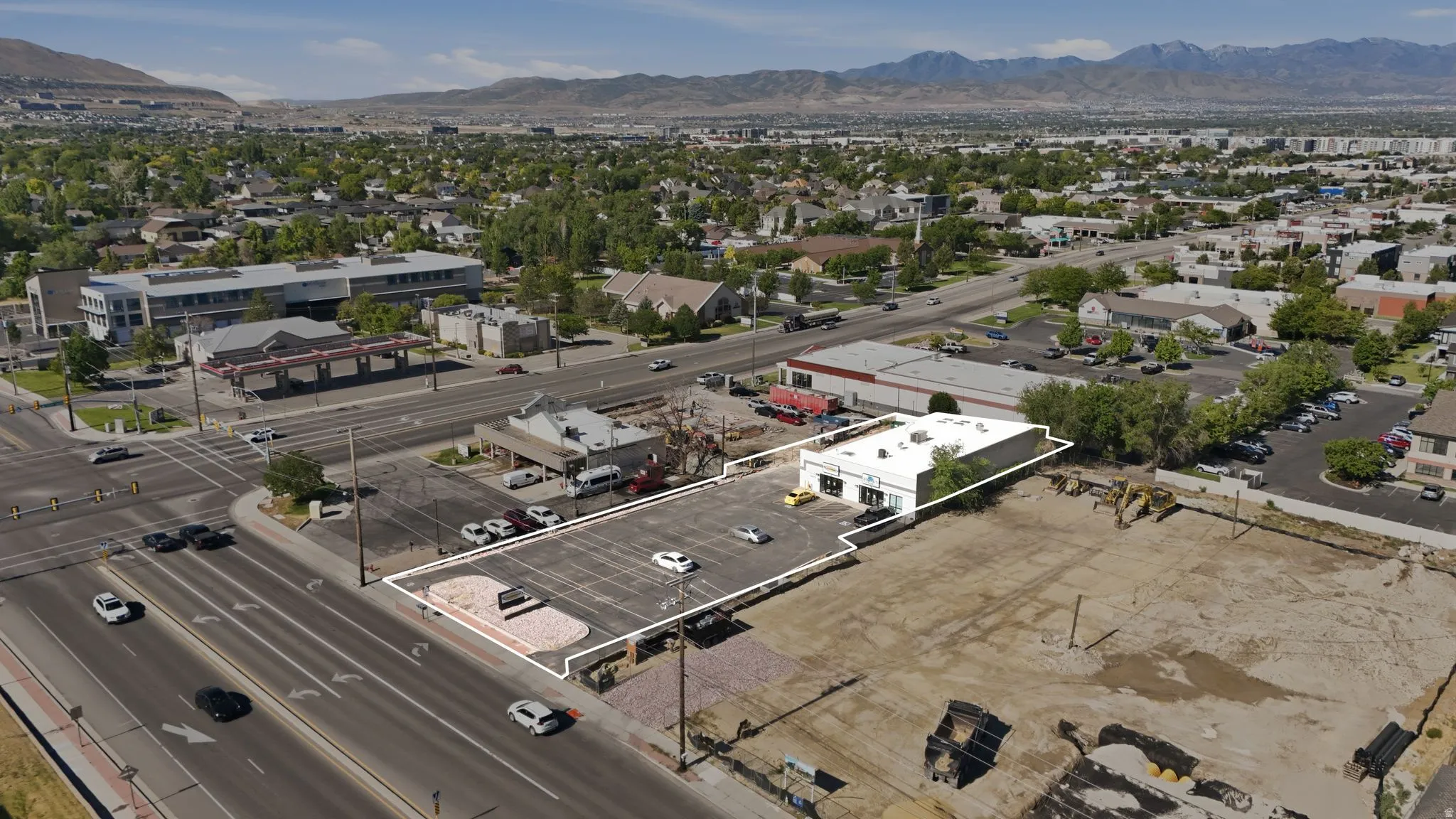 Commercial property featuring a white-painted building with prominent signage, a paved parking lot, and direct street frontage