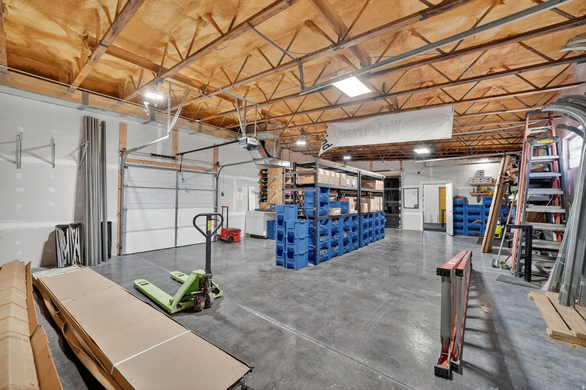 Spacious interior featuring a high ceiling with exposed wood trusses and insulation