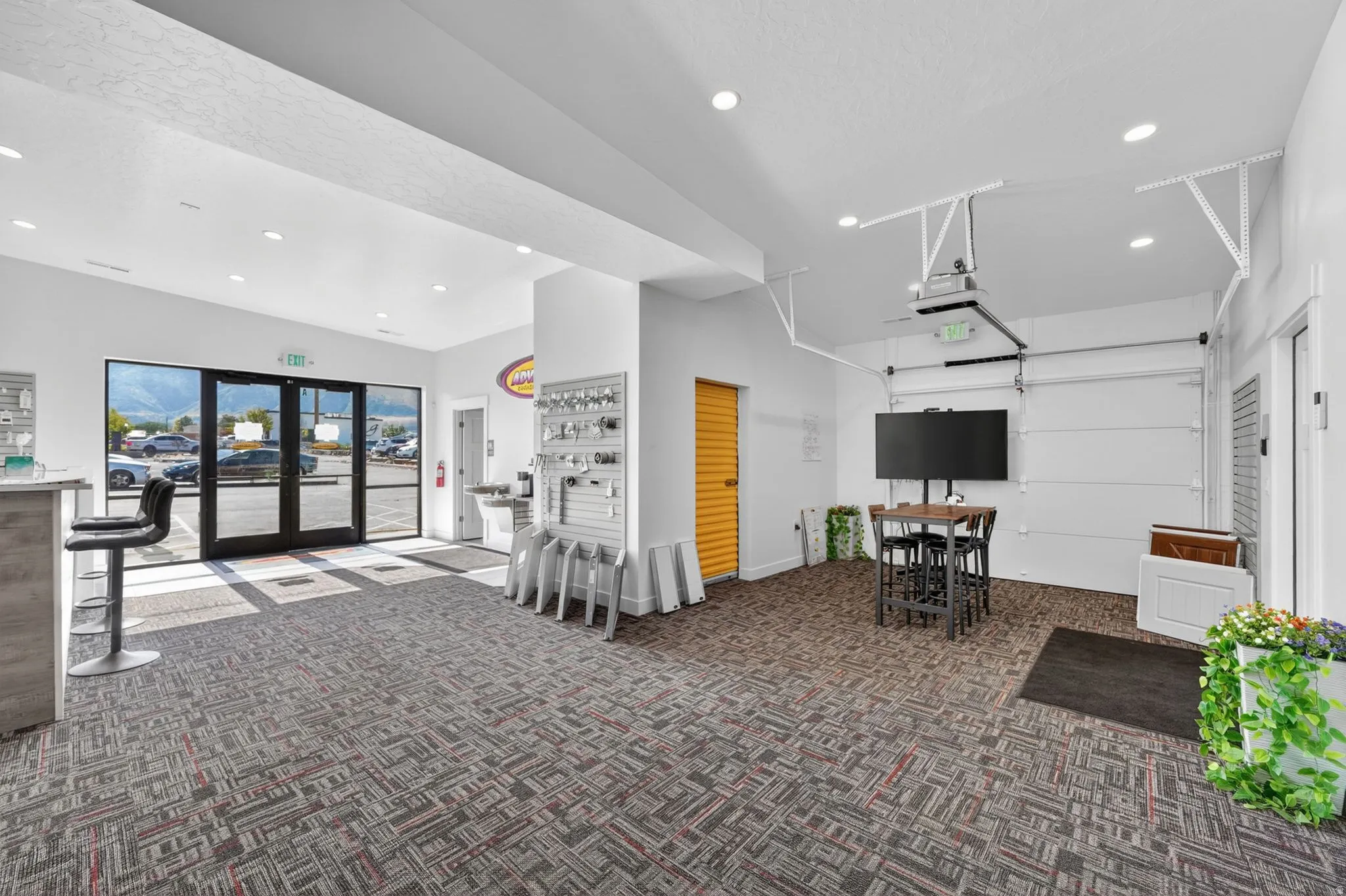 Spacious interior featuring patterned carpet flooring, recessed lighting, large glass entry doors, and a built-in counter with bar seating