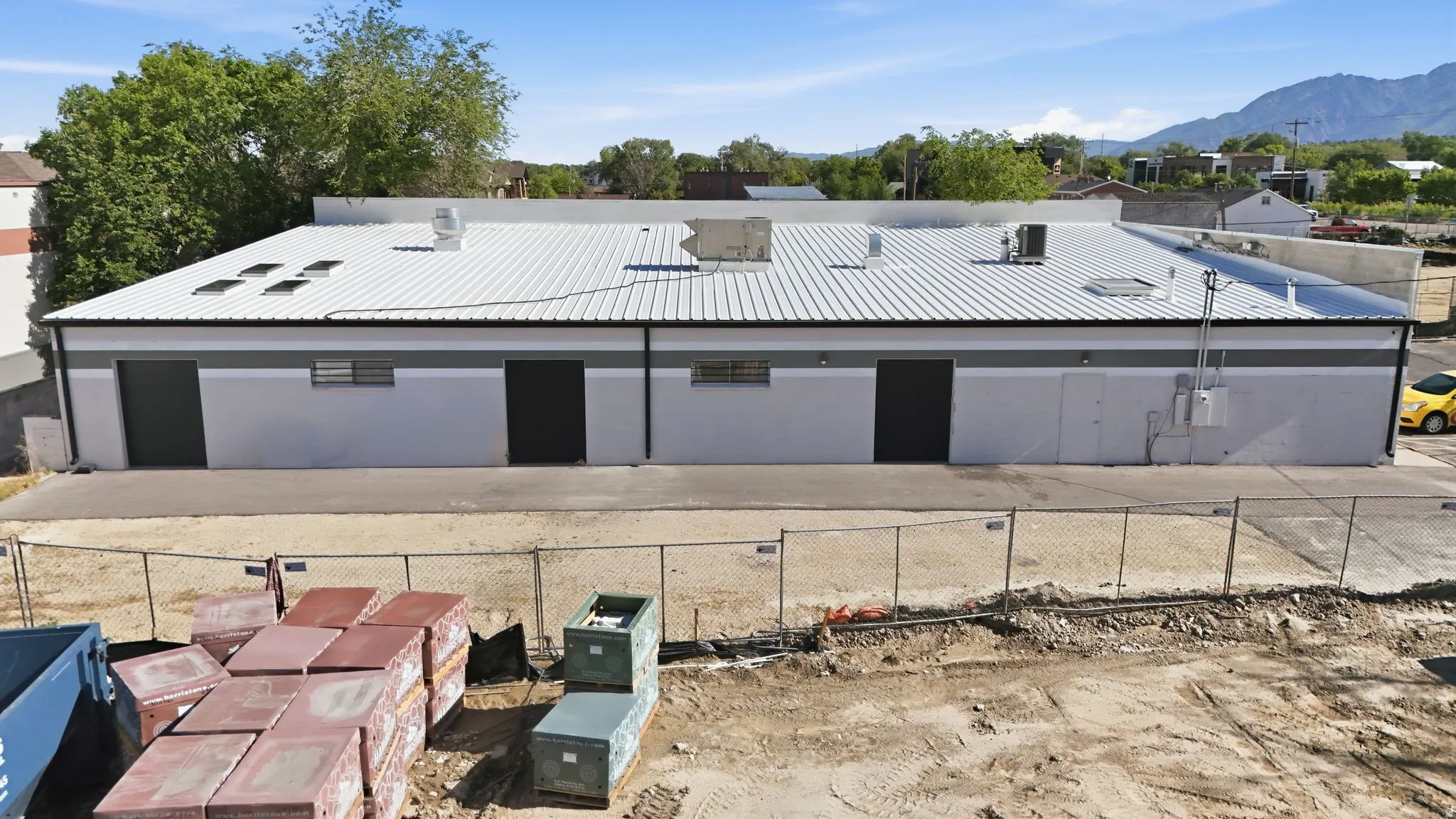 Commercial building featuring a metal roof, multiple skylights, and a light-toned exterior with dark trim
