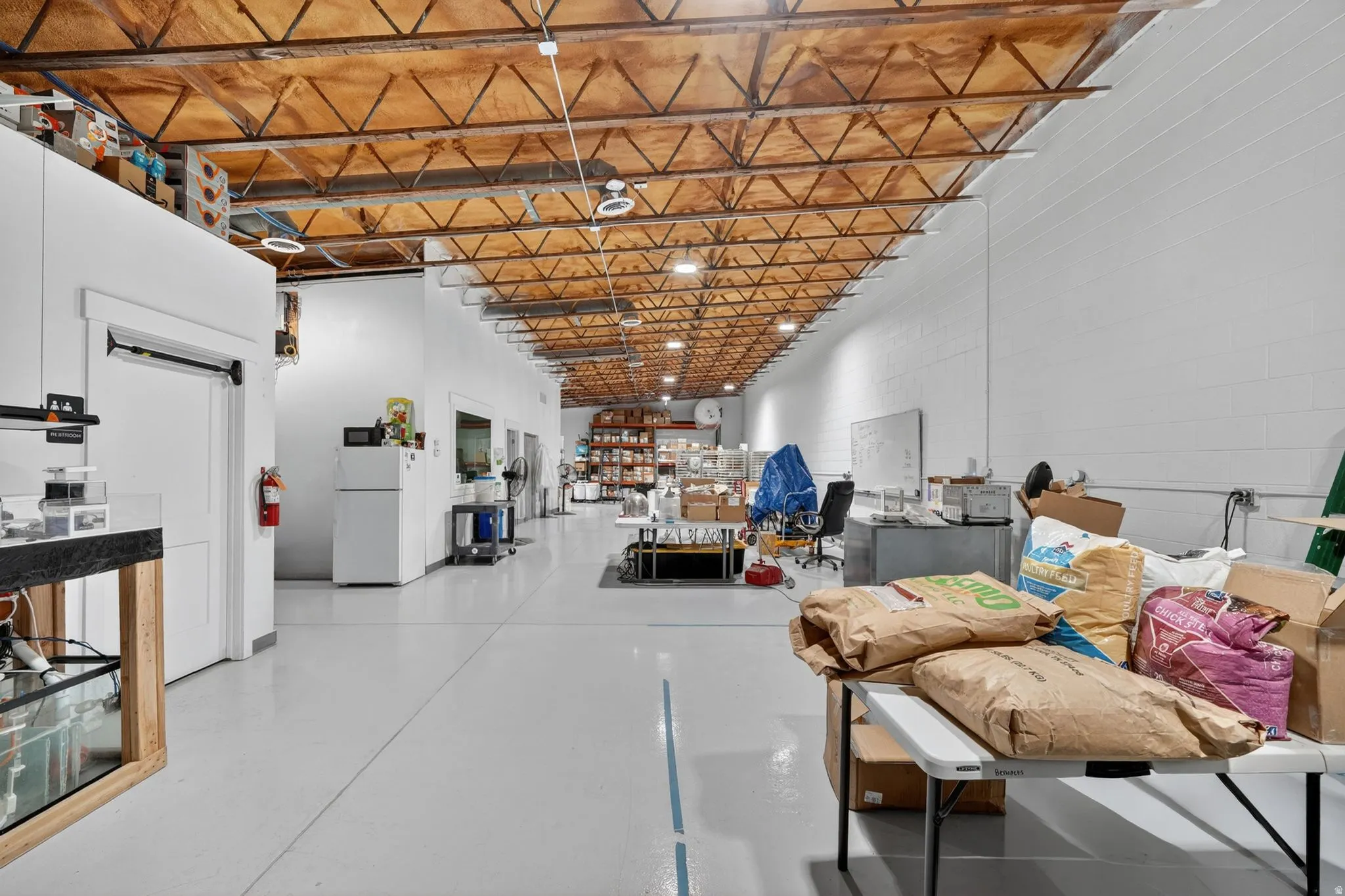 Spacious open-plan interior featuring a high exposed ceiling with structural trusses and recessed lighting