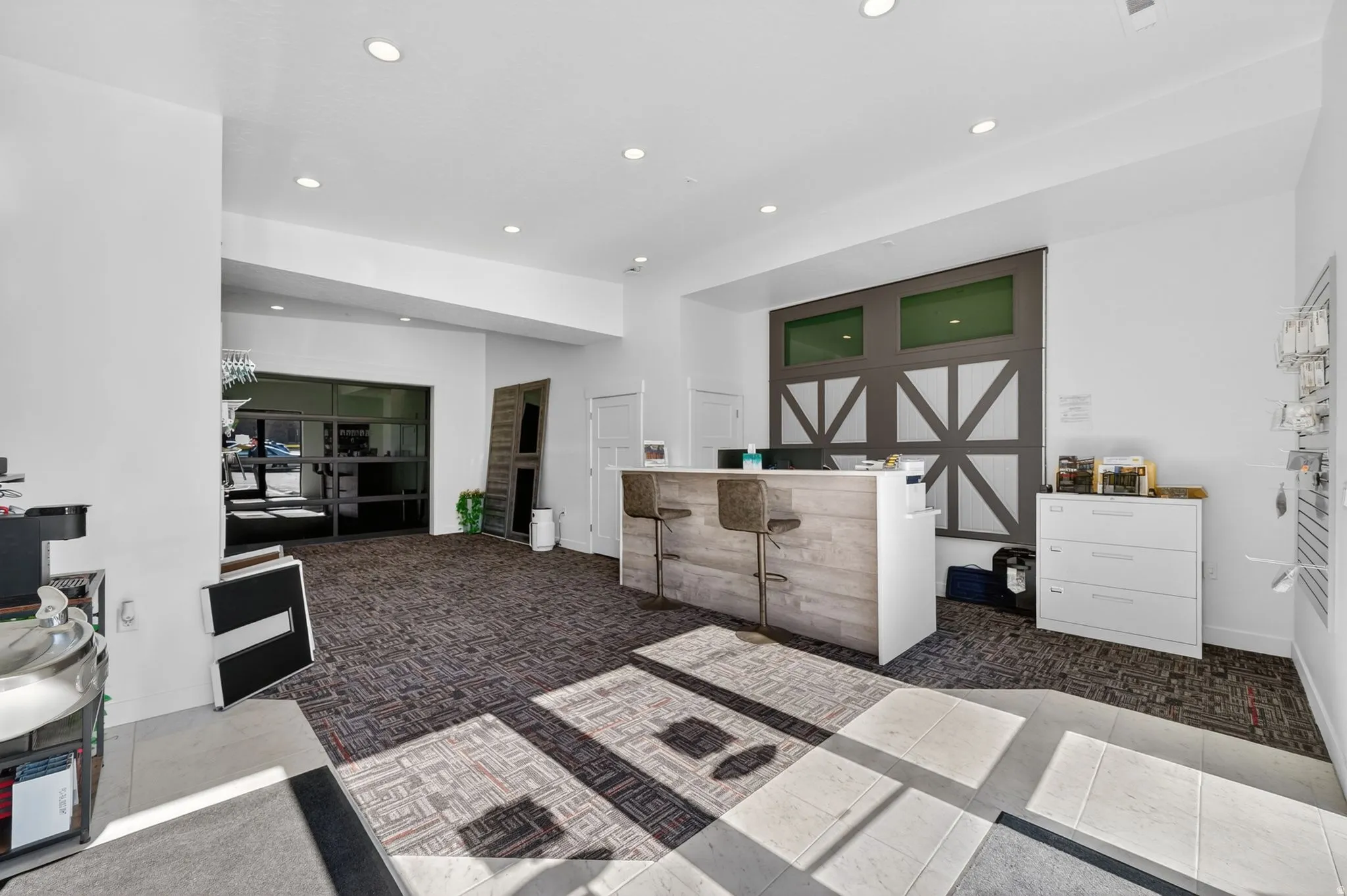 Reception area featuring a wood-finish front desk, recessed lighting, carpet flooring, and a decorative wall panel with transom windows