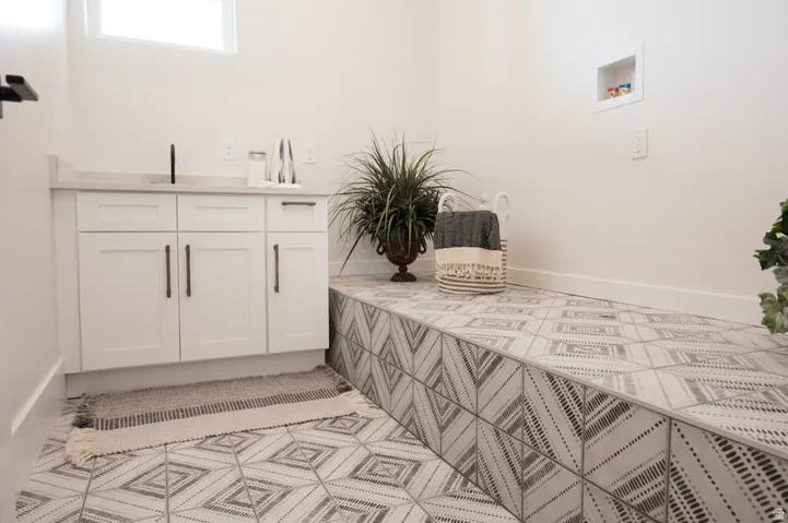 Laundry space featuring decorative geometric tile flooring extending to a raised platform