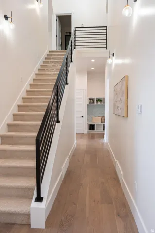 Staircase featuring carpeted treads, a contemporary black metal railing, and white risers