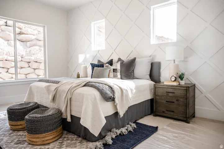 Accent wall with geometric paneling, multiple windows for abundant natural light, and light wood-finish flooring