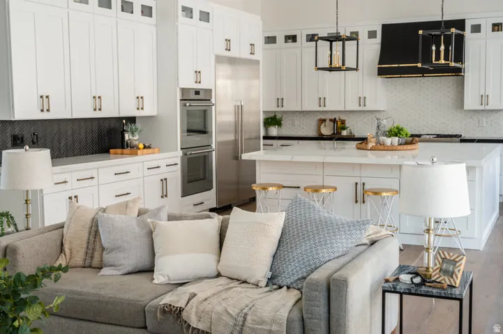 Open-concept living space with a kitchen island, white cabinetry, dark backsplash, stainless steel appliances, and wood-finish flooring