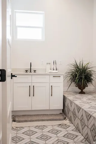 White cabinetry with dark bronze hardware, a sleek black faucet, and a light-toned countertop