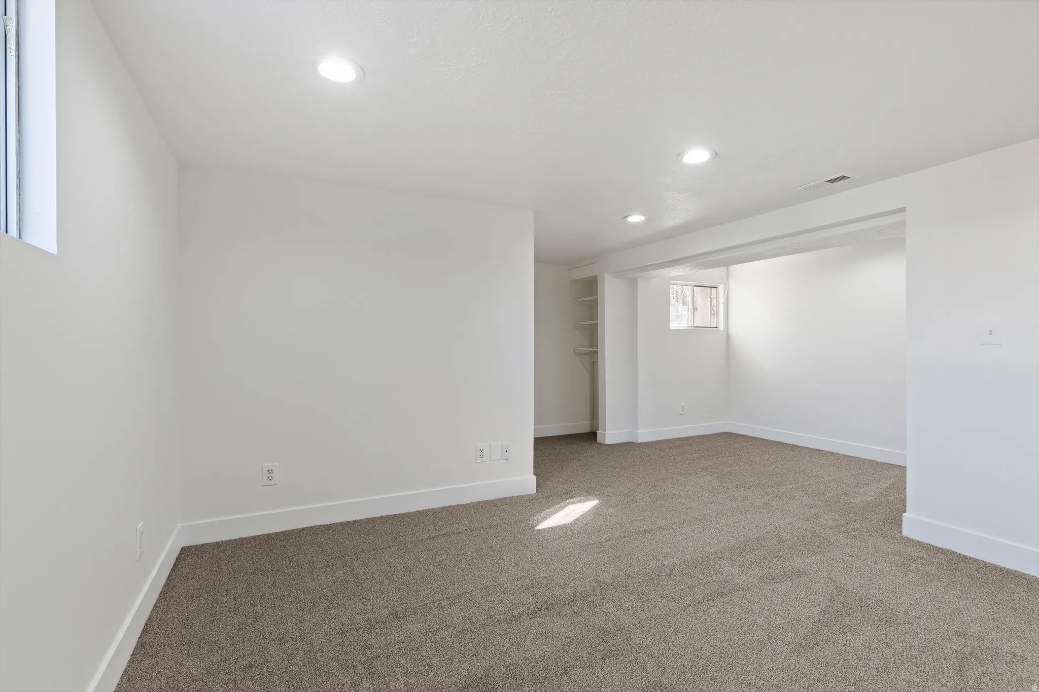 Spacious interior featuring neutral carpeting, recessed ceiling lighting, and crisp white walls