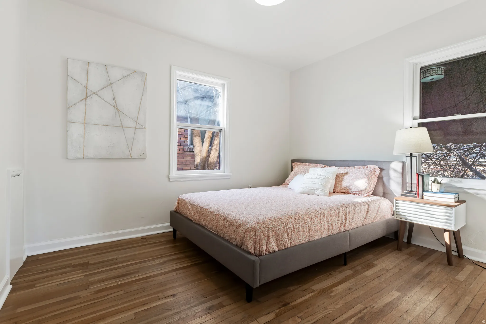 Bright room featuring wood-finish flooring, white baseboards, and two windows with white trim