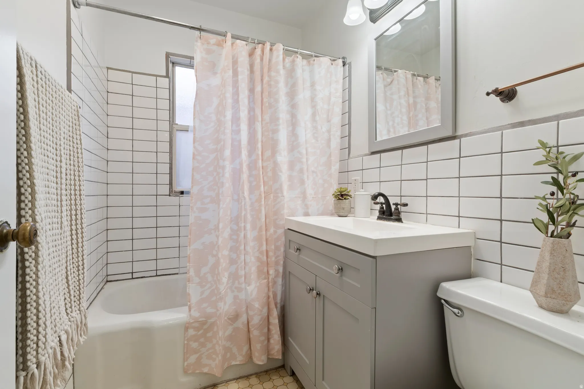 Bathroom featuring a white subway tile surround, white bathtub, gray vanity with integrated sink, and hexagon floor tiling