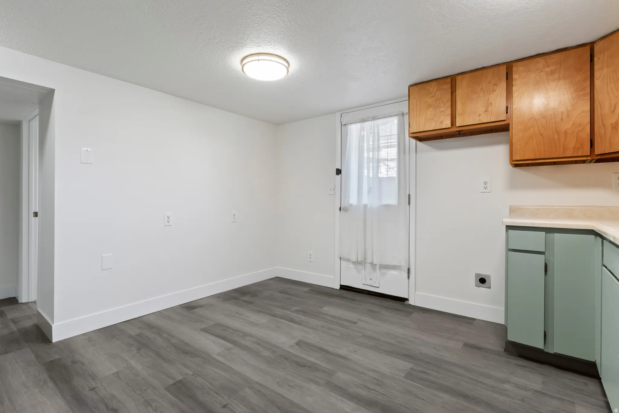 Room featuring wood-finish flooring, white walls, and a flush-mount ceiling light