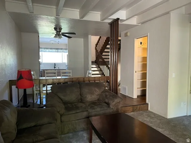 Living area/ dining/kitchen, built-in pantry with shelving and open staircase.