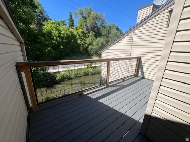 Primary bedroom deck featuring composite decking and a wood-frame railing with wire infill