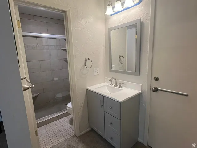 Primary Bathroom featuring a gray vanity with an integrated sink, brushed nickel faucet, and walk-in shower.