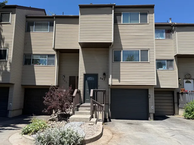 Multi-level townhome exterior featuring neutral siding, multiple windows, and an integrated garage