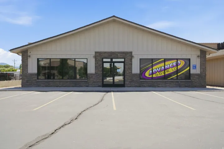 Commercial building featuring a stone and vertical siding facade, a gabled roofline, and multiple large storefront windows