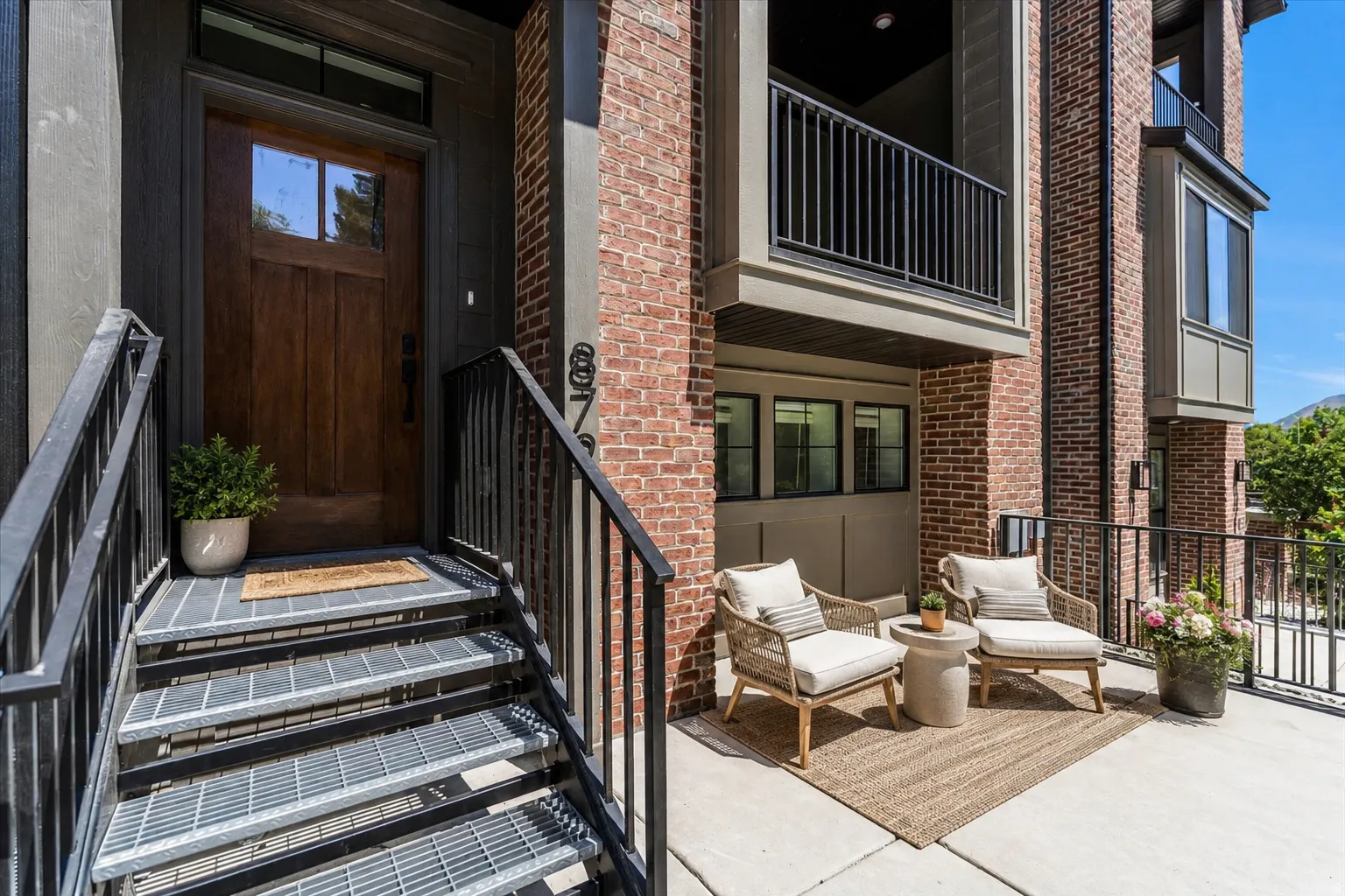 Brick exterior featuring a wood-panel entry door with glass inserts, transom window, and exterior lighting