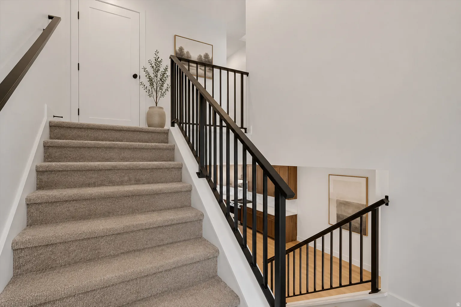 Carpeted staircase with dark metal balusters and handrails, complemented by white walls and trim