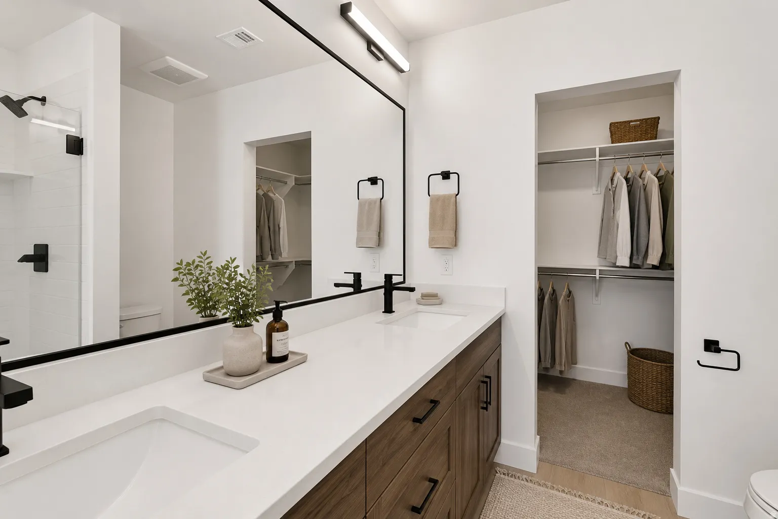 Dual undermount sinks set within a white countertop, complemented by a wood-finish vanity with dark hardware