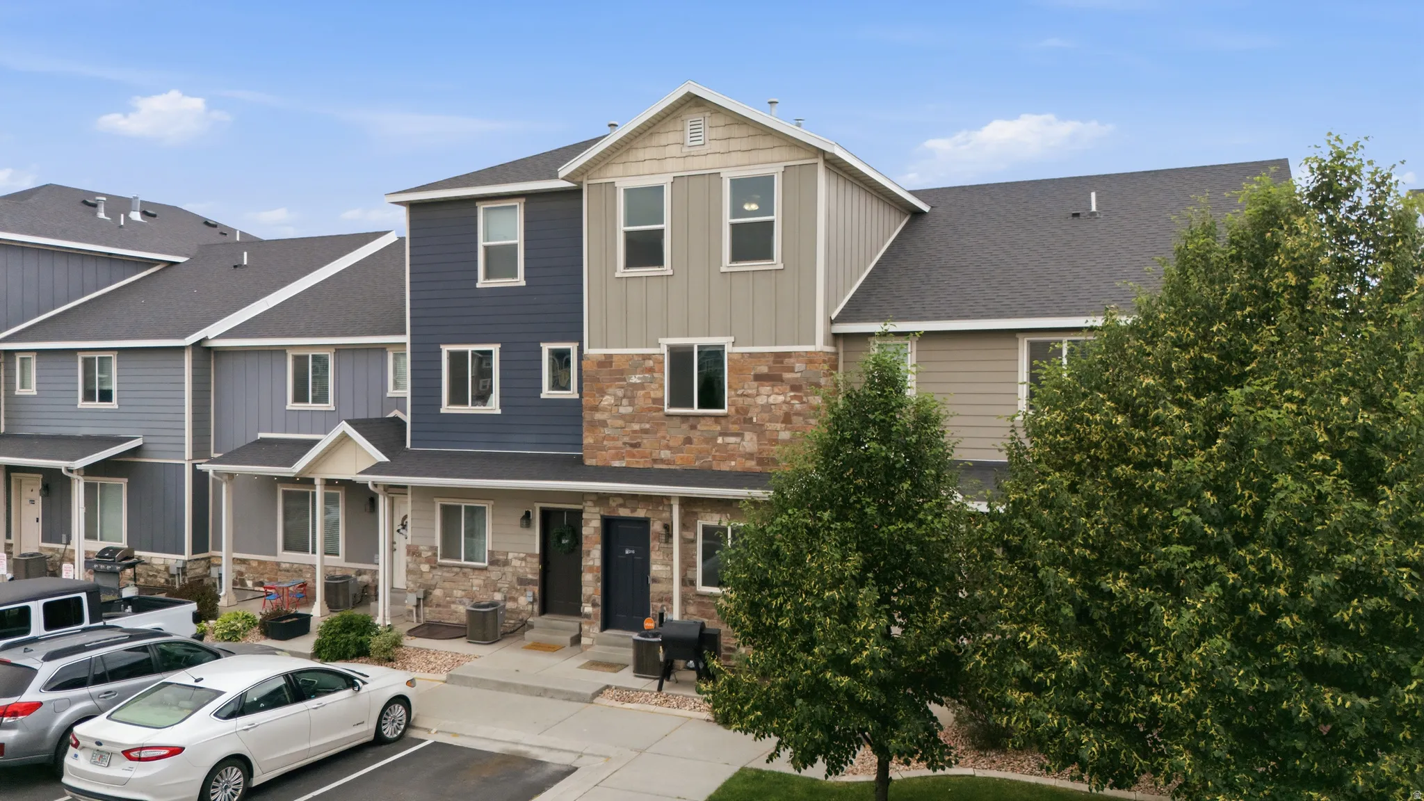 Multi-story townhome featuring varied siding textures and stone facade elements