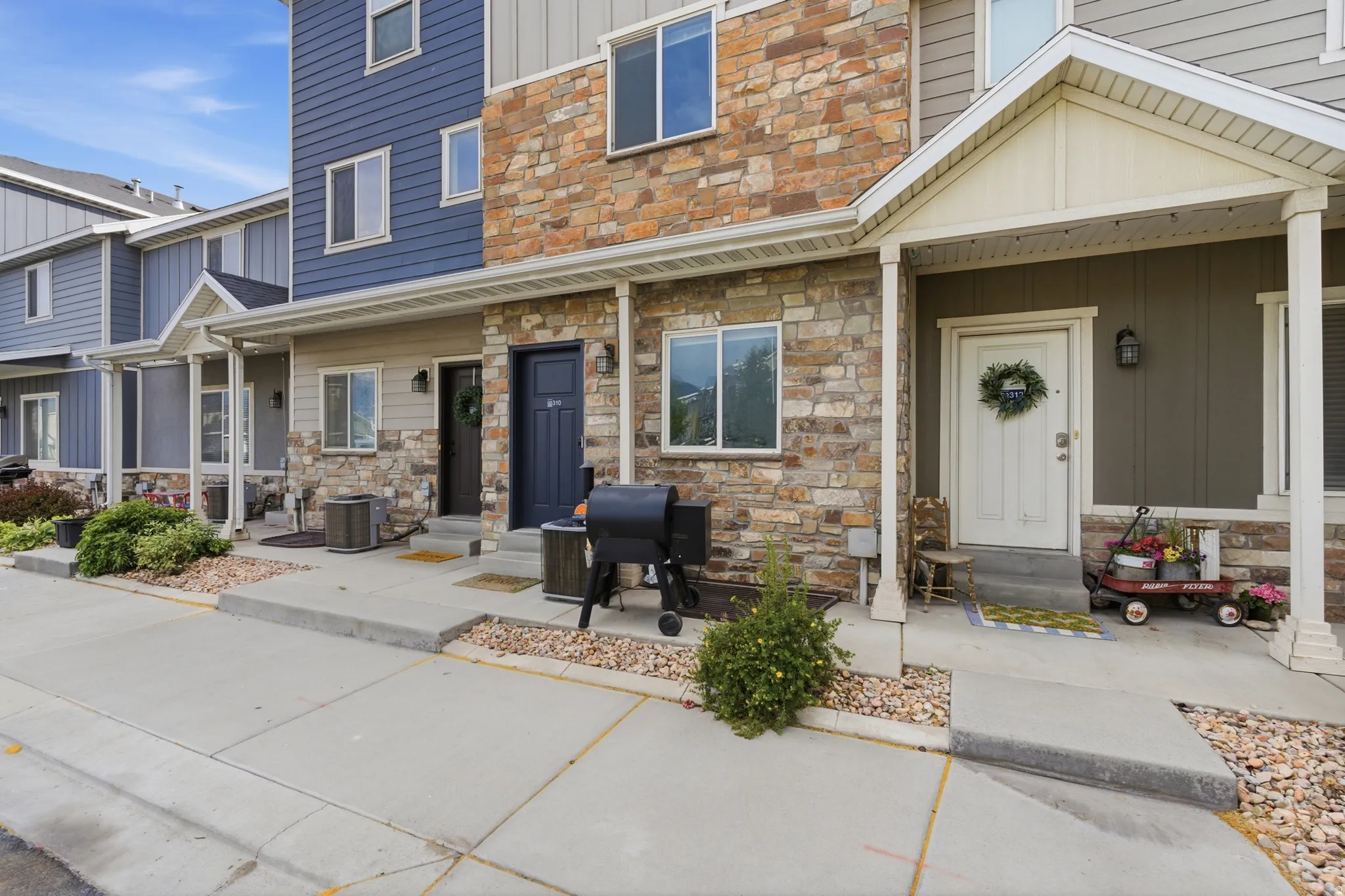 Townhome exterior featuring varied siding materials including stone veneer, vertical siding, and horizontal siding