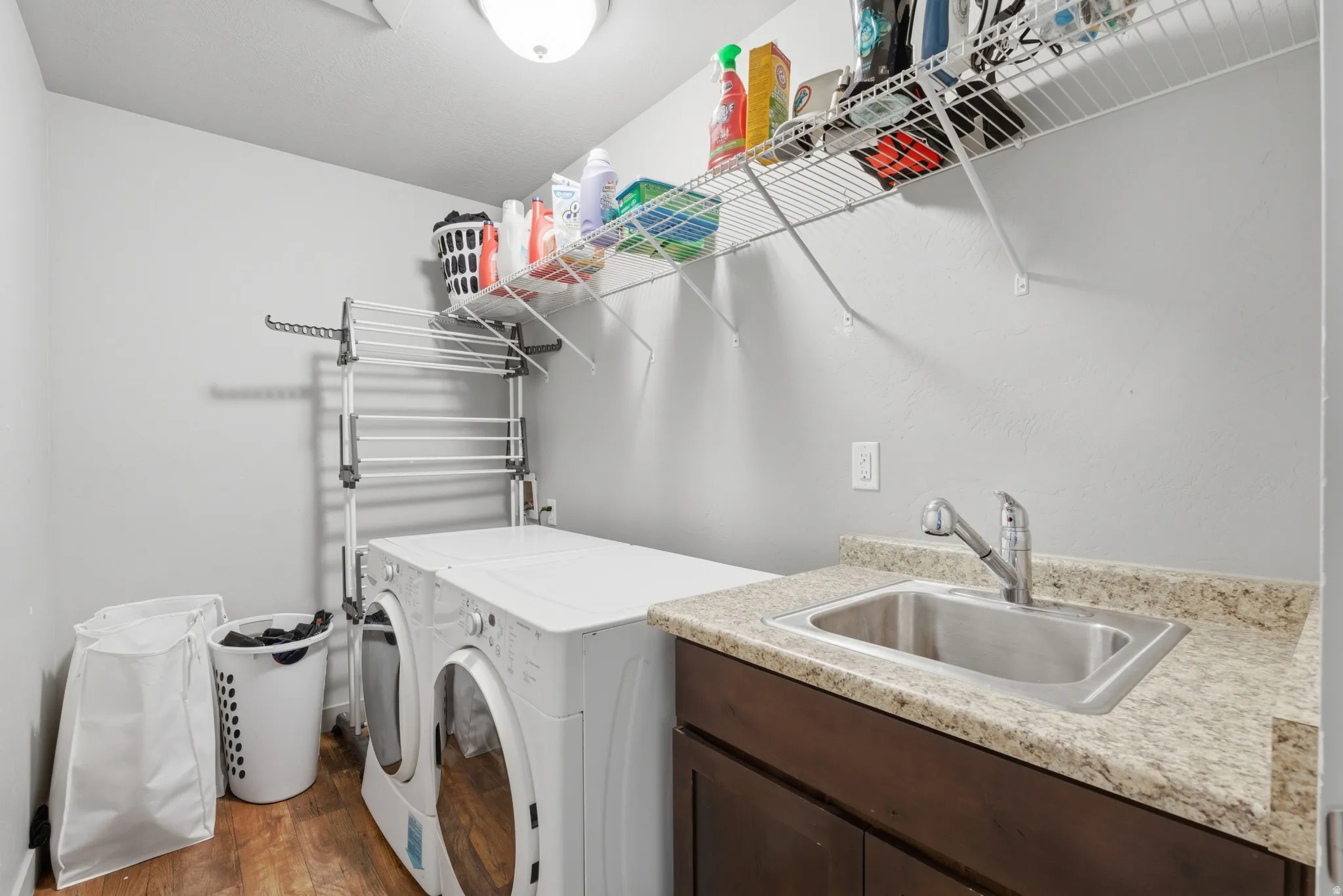 Dedicated laundry space featuring wood-finish flooring and light gray wall paint
